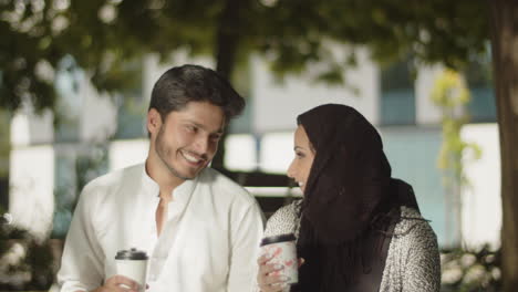 romantic muslim couple having coffee in park on warm summer day.