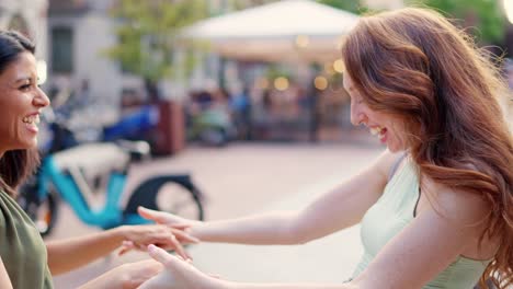 two happy women friends laughing and holding hands outdoors