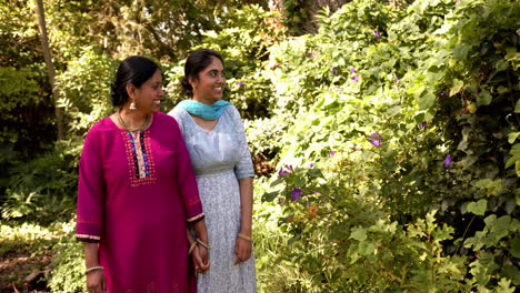 walking in garden, two indian mother and daughter smiling and enjoying nature together