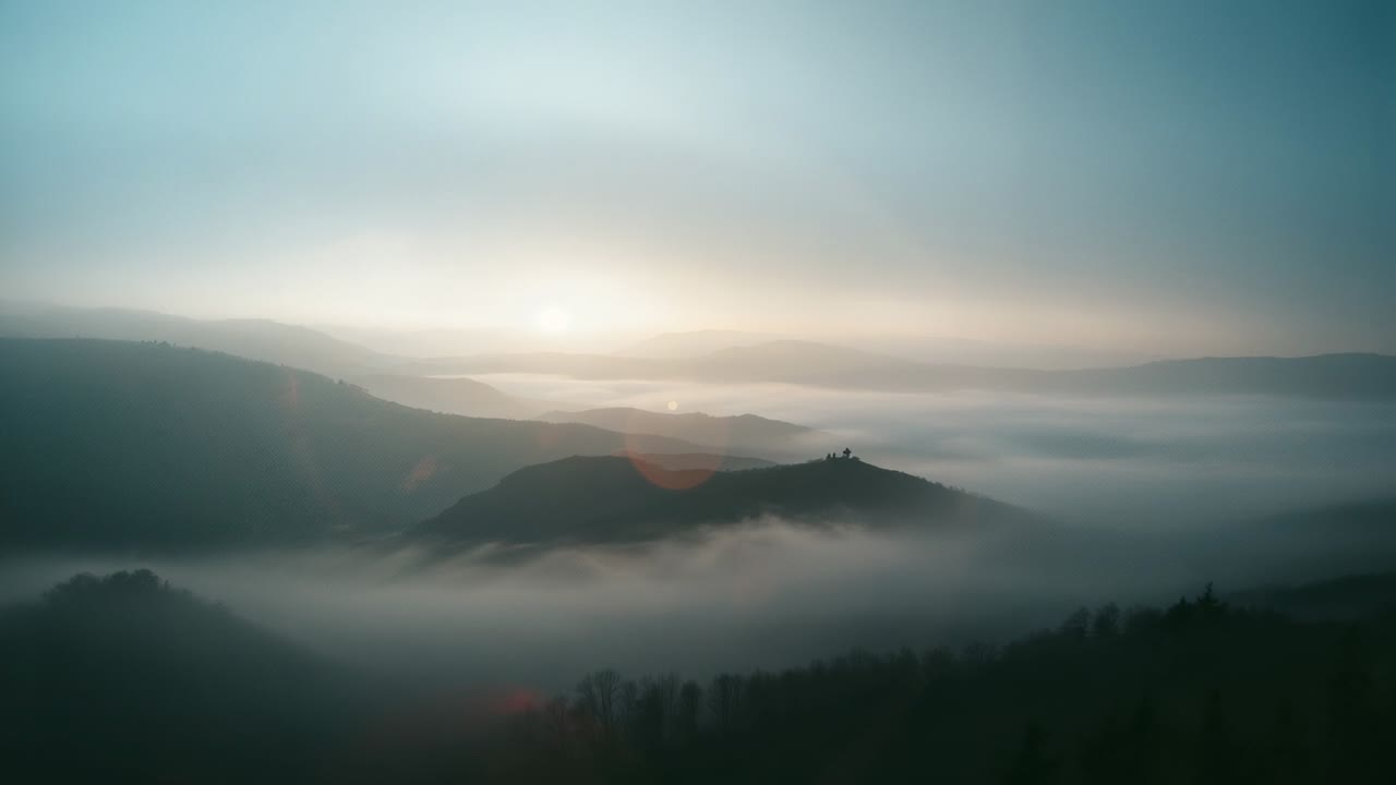 Revealing misty rolling hills and layered ridges at dawn with rising sun casting golden fog