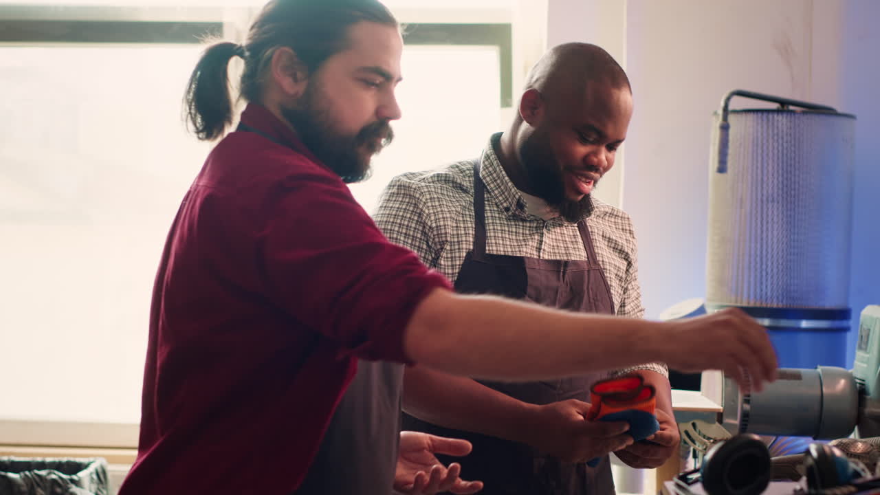 Cabinetmaker ensures apprentice uses safety earmuffs before starting work