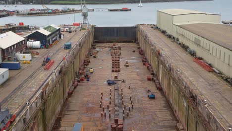 big empty dry dock in falmouth shipyard, with industrial equipment and cranes for shipbuilding