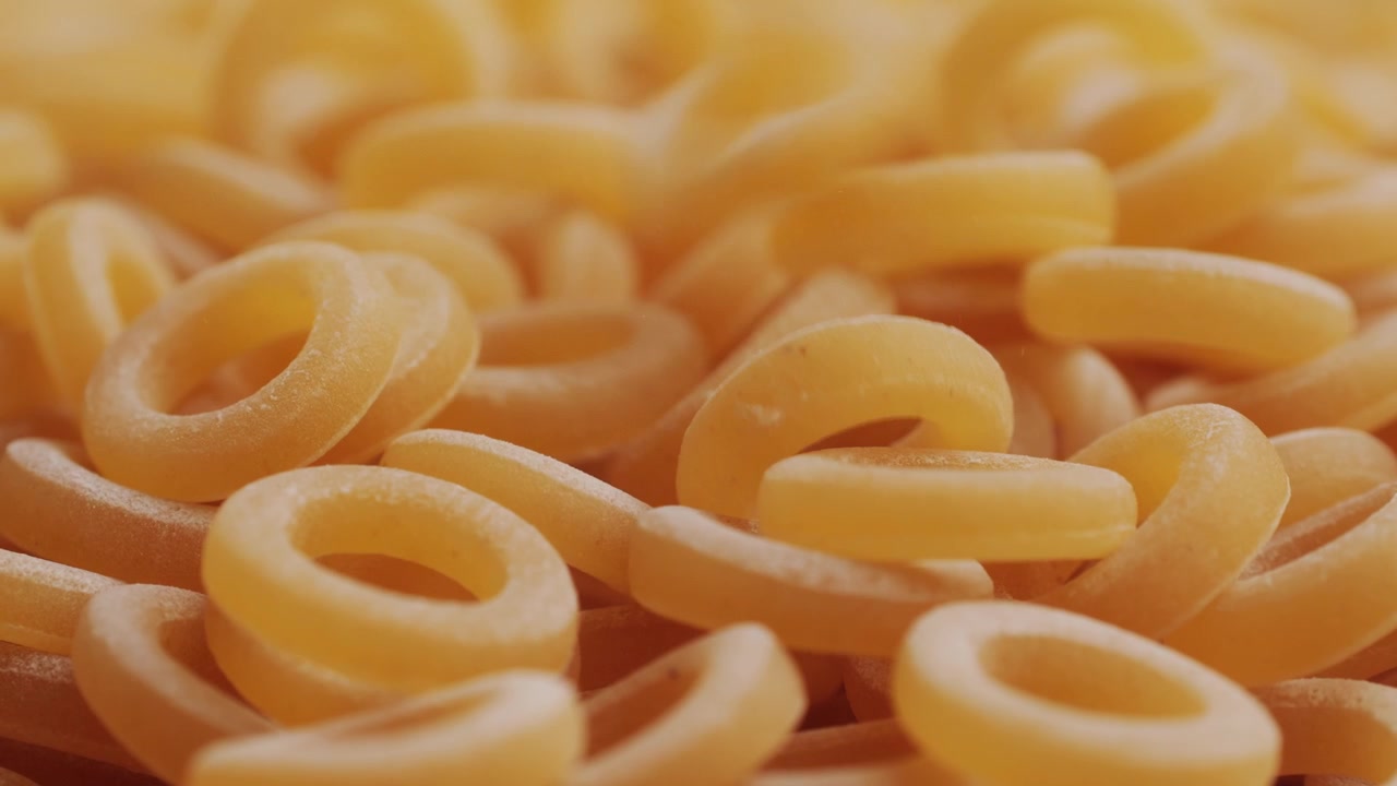 Pasta integrale biologica, maccheroni di semola di grano duro, penne rigate crude in una ciotola di legno. Filmato 4k di alta qualità
