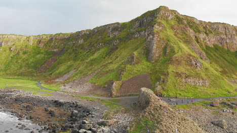 Toma-Aérea-De-Camiones-De-Turistas-Caminando-En-La-Costa-De-La-Calzada-En-Irlanda-Del-Norte