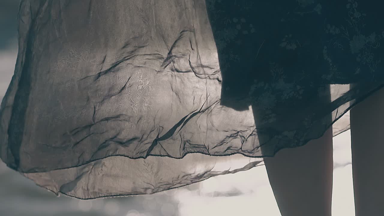 девушки ноги и юбка размахивают в ветре против реки медленное движение