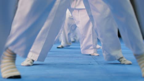 close-up of several children in karate kimono jumping and changing posture on site