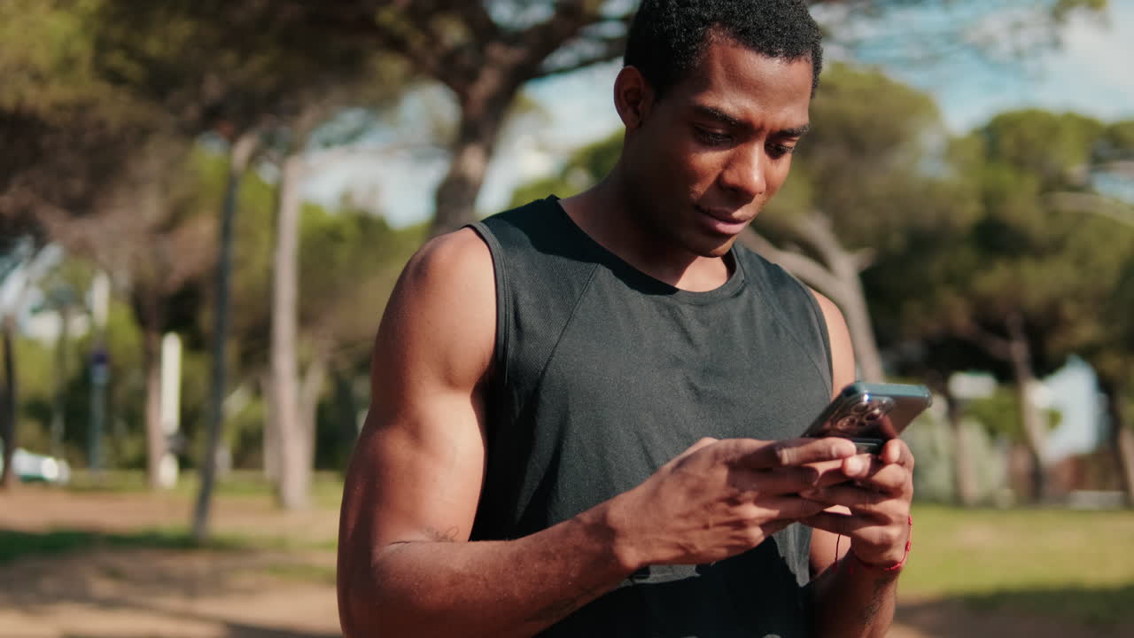 Muscular Black Man Checks Phone In Park