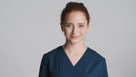 redheaded doctor in front of camera on gray background.