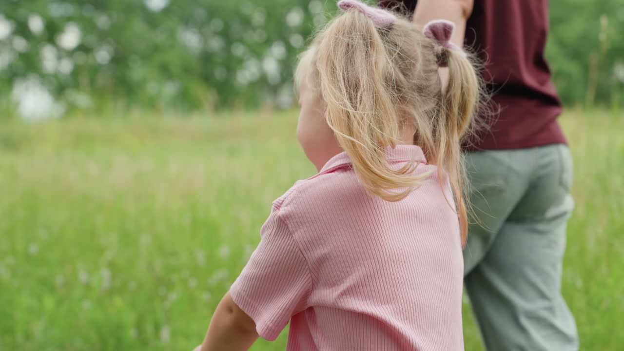 badante bianca e bambina si tengono per mano su un sentiero erboso, primo piano delle trecce e espressione curiosa, guida protettiva mentre la bambina saltella tra i fiori di campo, passi leggeri su un sentiero sterrato, luminoso