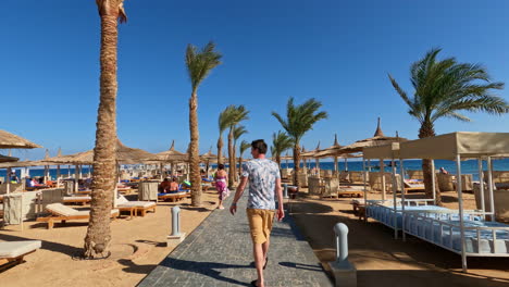 White-man-in-a-summer-t-shirt-walks-along-a-path-on-the-beach-on-a-sunny-day