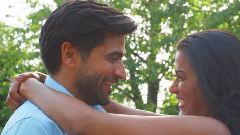 loving couple hugging outdoors in summer garden or countryside against flaring sun
