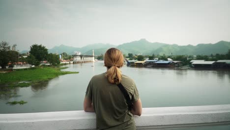 female tourist traveler looking over the khwae yai river in kanchanaburi, thailand