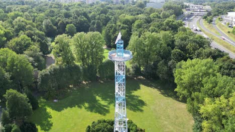 Aerial-Viev-of-Blue-and-White-Parachute-Tower-and-Traffic-View-in-the-Distance