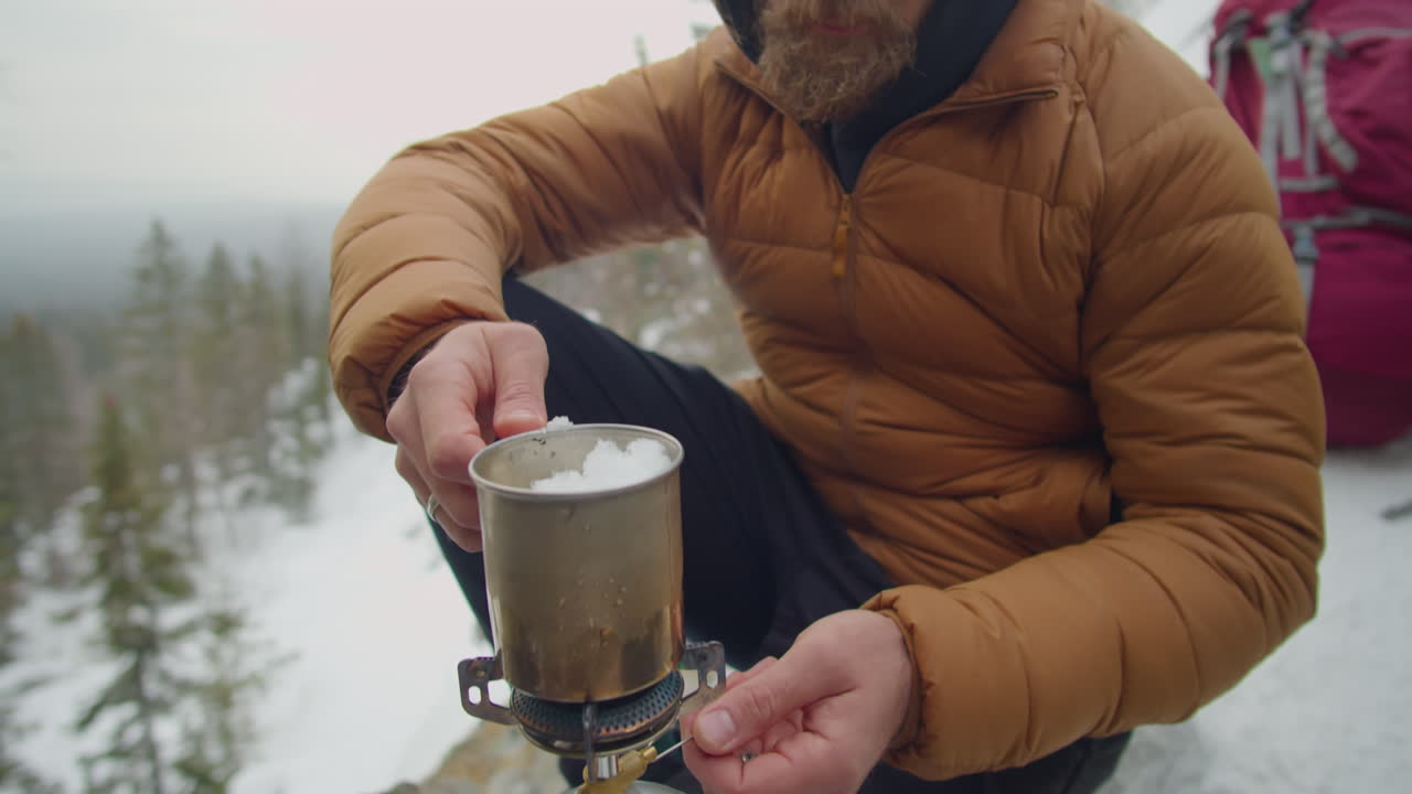 Man Using Gas Stove during Winter Camping in Mountains