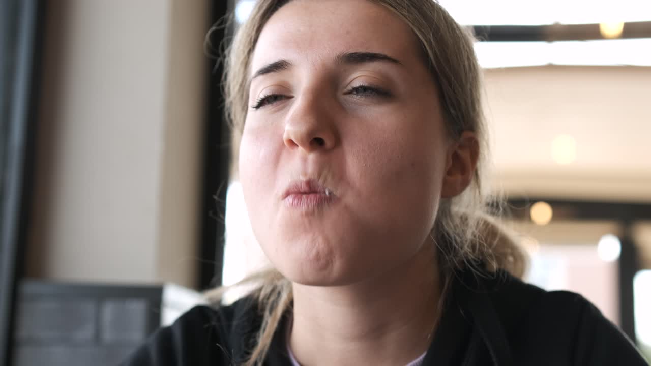 Young woman relishing a juicy burger while expressing delightful emotions