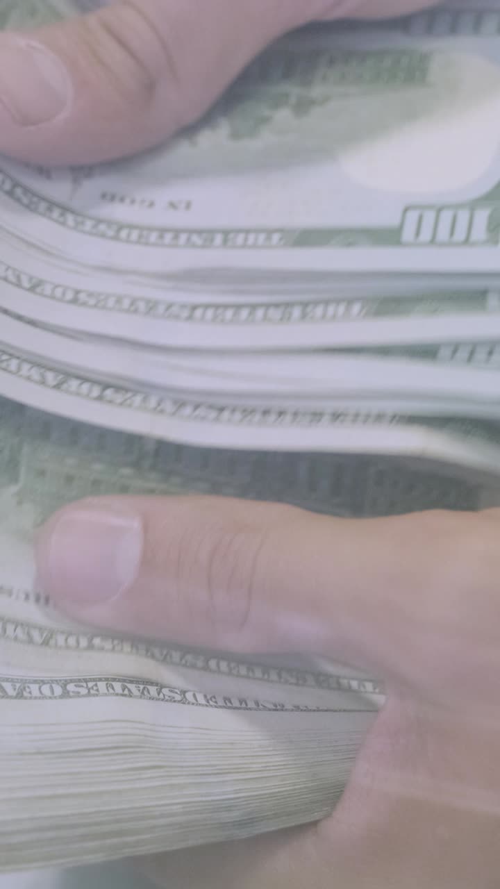 Hand holding a stack of US dollar bills