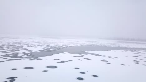 a flying wide shot looking out over frozen river during a snowstorm