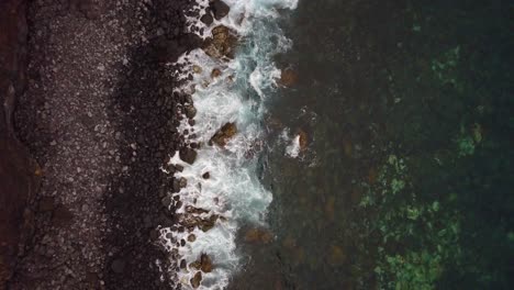 Vista-Aérea-Relajante-De-Arriba-Hacia-Abajo-De-La-Costa-De-La-Playa-Rocosa-Volcánica-Mientras-Las-Olas-Rompen-En-La-Orilla