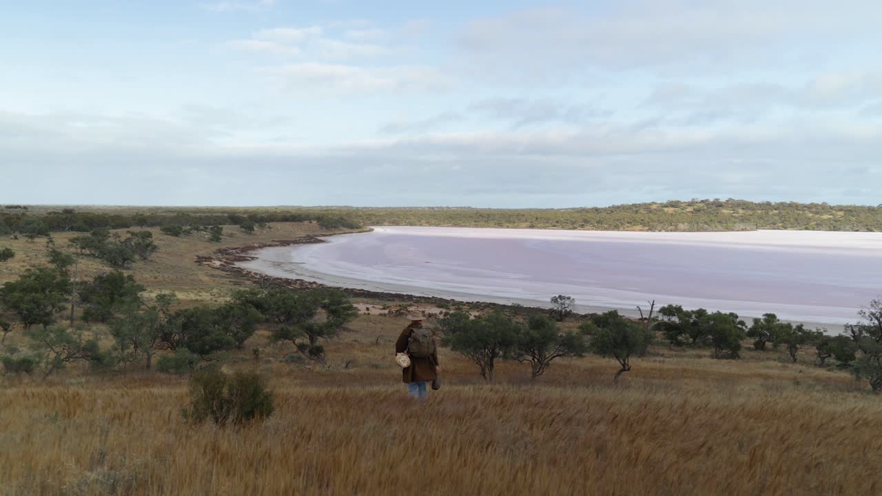 un swagman camina por el interior de australia más allá de un lago salado