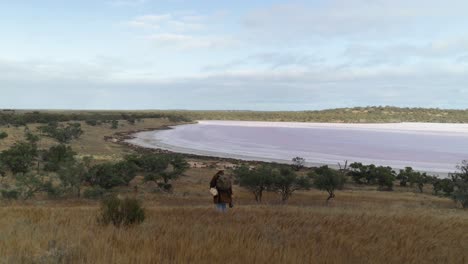 a swagman walks through the australian outback past a salt lake