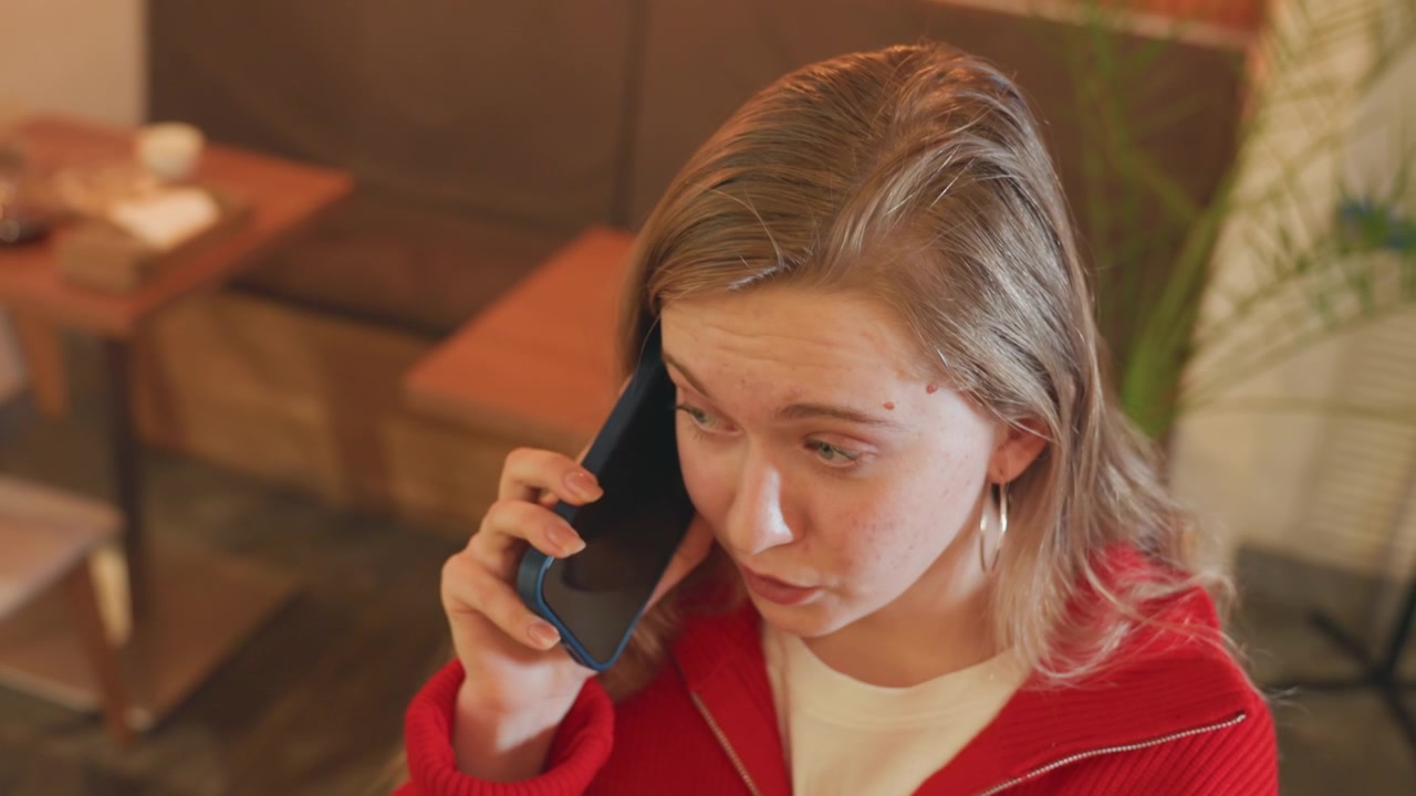 Młoda kobieta rozmawia przez telefon z poważnym wyrazem twarzy
