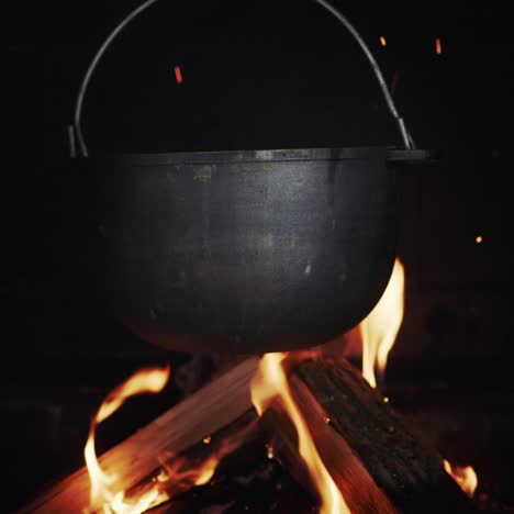 Una-Tina-De-Hierro-Fundido-Con-Caldo-Hirviendo-Cuelga-En-Una-Estufa-De-Leña-Sobre-Un-Fuego-Abierto