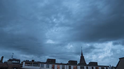 grey ominous sky and turbulent storm clouds blanket city buildings, time lapse day to night