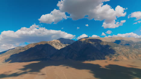 White soft cumulus clouds soaring over the beautiful mountains. Cloudscape throwing shadows on the rocks. Fantastic azure skies at backdrop.
