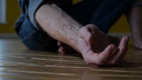 Close-up of a human hand resting on a wooden floor bathed in sunlight