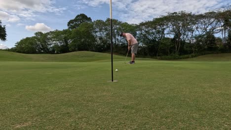 a golfer sinks a putt and celebrates joyfully.