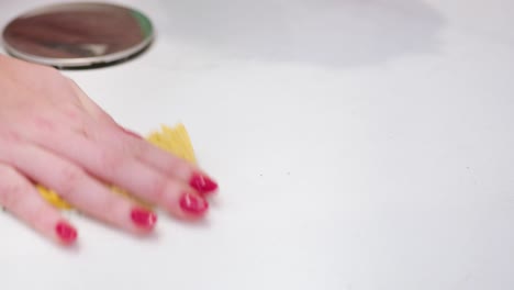 Woman-with-red-nails-use-sponge-to-clean-white-bathtub,-close-up