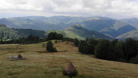 stunning view over the mountains and a meadow with flowers and traditional haystacks