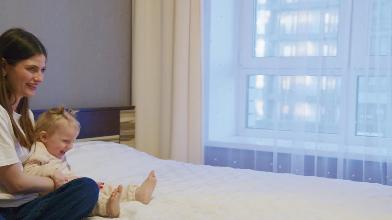 Happy Mother and Baby Playing and Laughing on Bed