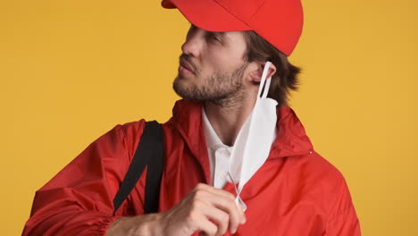 caucasian delivery man in front of camera on yellow background.