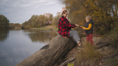 little-boy-is-playing-with-his-mother-at-autumn-forest-walking-together-in-park-happy-woman-and-child-smiling-and-laughing-weekend-trips-at-nature