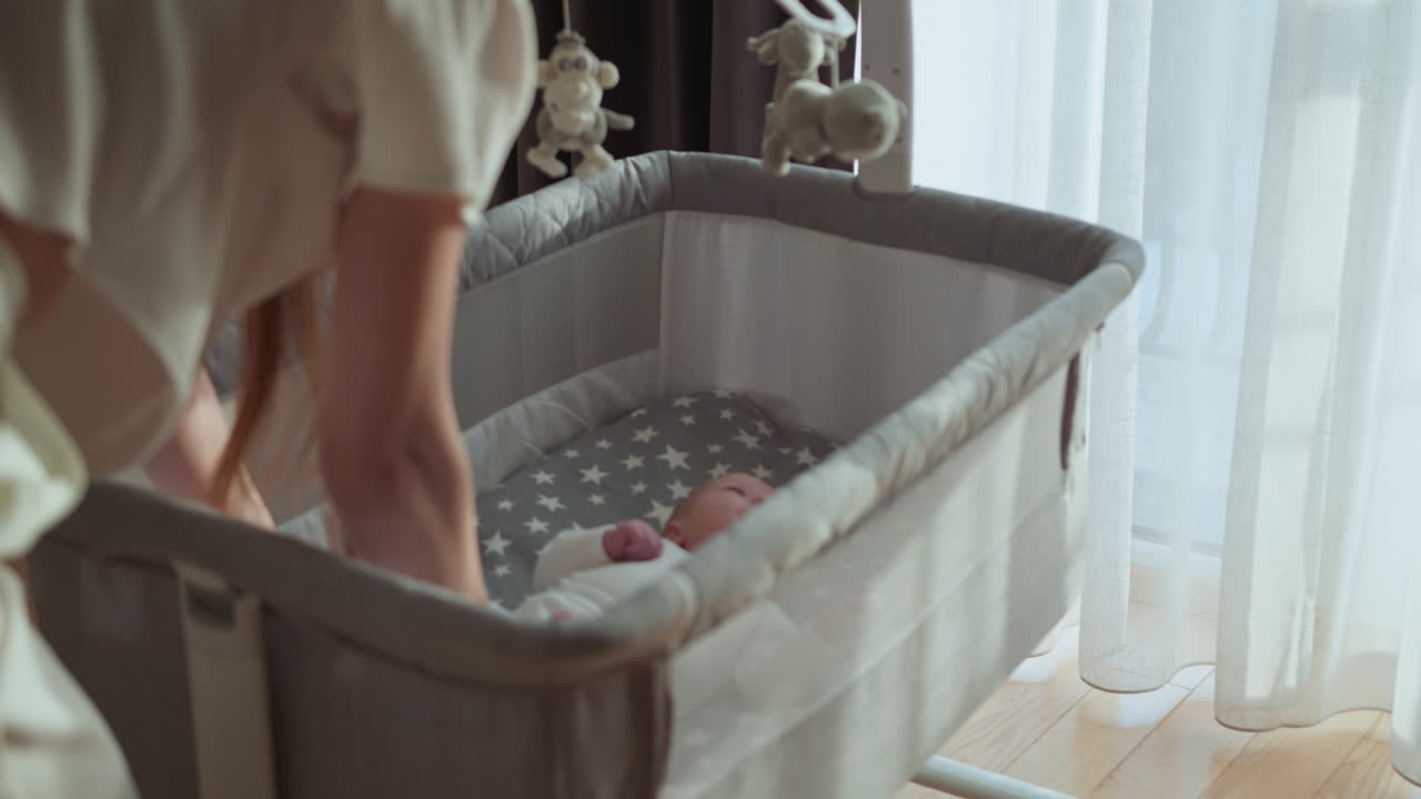 Donna che prepara la culla per il bambino, circondata da palloncini festivi e un orsetto di peluche, creando una cameretta gioiosa.