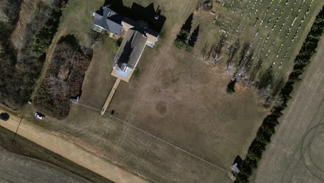 top-down aerial view from high above showing black car driving along a dusty dirt road and passing st boniface church in flagstaff county, alberta