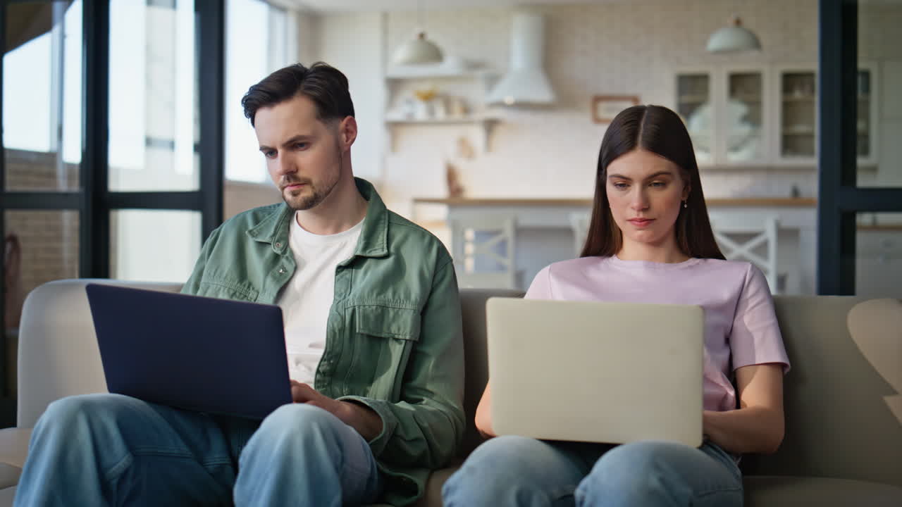 Involved pair working remotely at room interior. Serious man woman doing tasks