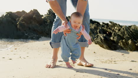 Vorderansicht-Eines-Kaukasischen-Vaters-Mittleren-Erwachsenen,-Der-Seinem-Baby-Hilft,-An-Einem-Sonnigen-Tag-Am-Strand-Spazieren-Zu-Gehen-4k