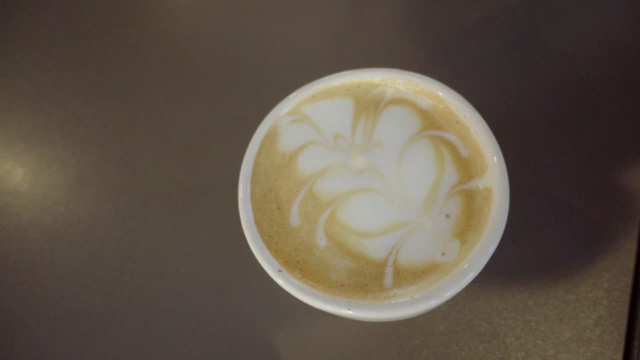 Top view of barista making latte art on coffee cup with milk foam