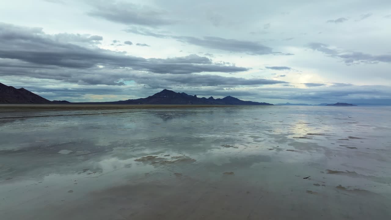 Wide Aerial drone shot of the famous Bonneville Salt Flats in Utah near Wendover, Utah, flooded from rain, creating mirage reflections with mountains in the background on a stormy spring evening