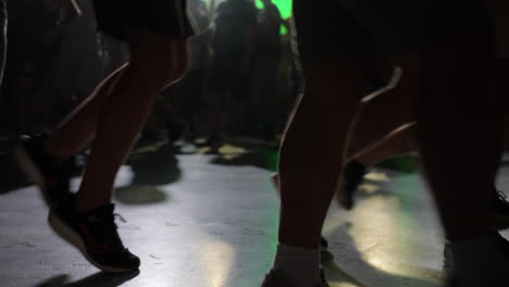 feet dancing on club floor with green lights