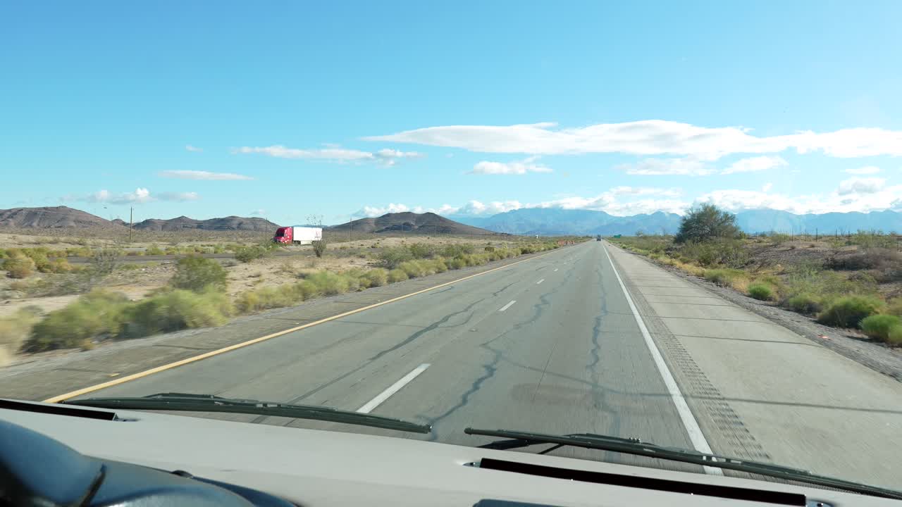 Guida POV su una lunga autostrada nel deserto verso le montagne