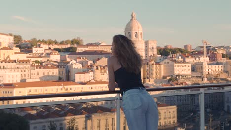 happy woman standing on the balcony with view on the city lisbon, portugal