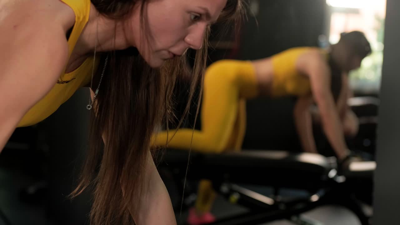 Strong athletic woman doing back pumping exercises with a dumbbell as part of her fitness bodybuilding exercises