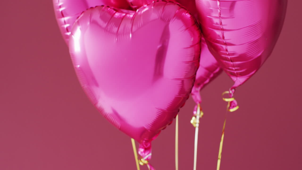 분홍색 배경에 떠다니는 네 개의 반이는 분홍색 심장 모양의 풍선의 비디오