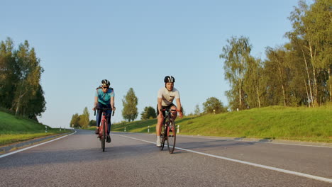 Radfahrer-Fährt-Auf-Rennrad,-Rückansicht.-Radfahrer-Treten-Im-Stadtpark-Mit-Rennrad-In-Die-Pedale.-Kamerafahrt-Eines-Radfahrers-Auf-Rennrad-Bei-Sonnenuntergang.-Intensives-Training-Eines-Radsportlers-Auf-Dem-Fahrrad