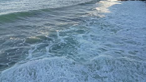 Drone-shot-of-waves-splashing-in-the-foreground-while-Sea-Lions-play-in-surf-during-King-Tide-in-La-Jolla,-Ca