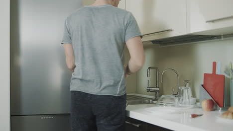 Smiling-man-taking-orange-out-of-fridge.-Handsome-man-cutting-fruit