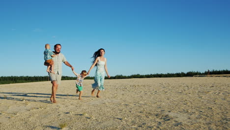 Cheerful-Family-Running-Across-The-Sand-Parents-And-Two-Young-Sons